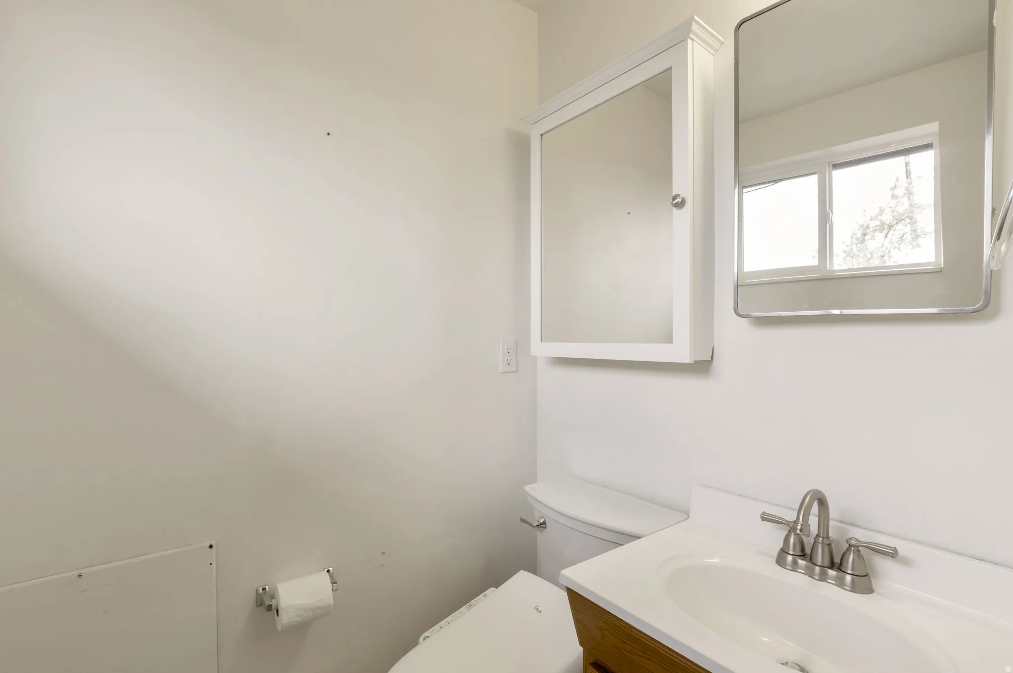 Bathroom featuring a wood-finish vanity with an integrated sink and brushed nickel faucet, a medicine cabinet, and a framed mirror