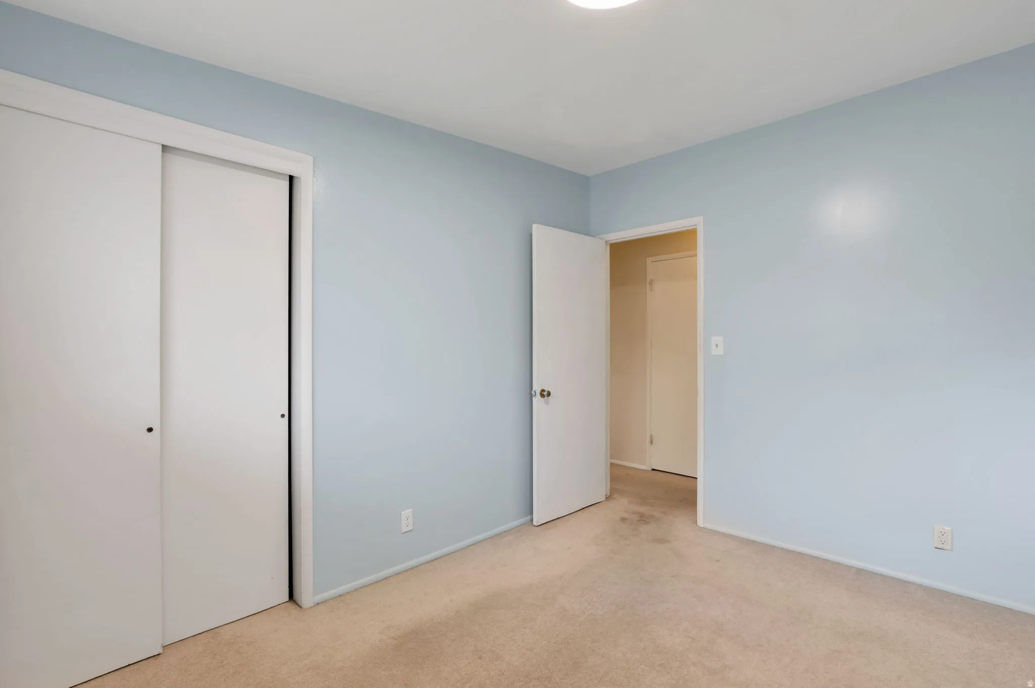 Interior room featuring light blue walls and beige carpet flooring