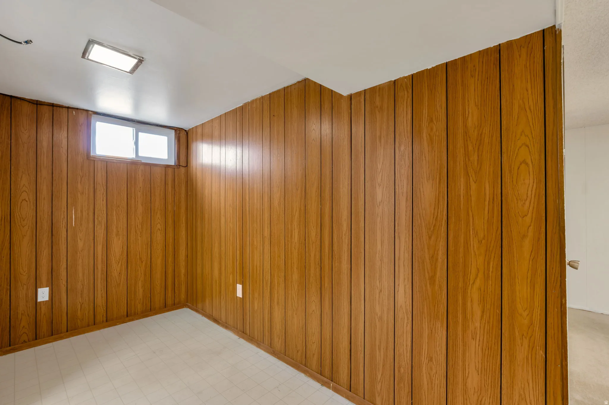 Room featuring wood-paneled walls, a white ceiling, and light-colored flooring