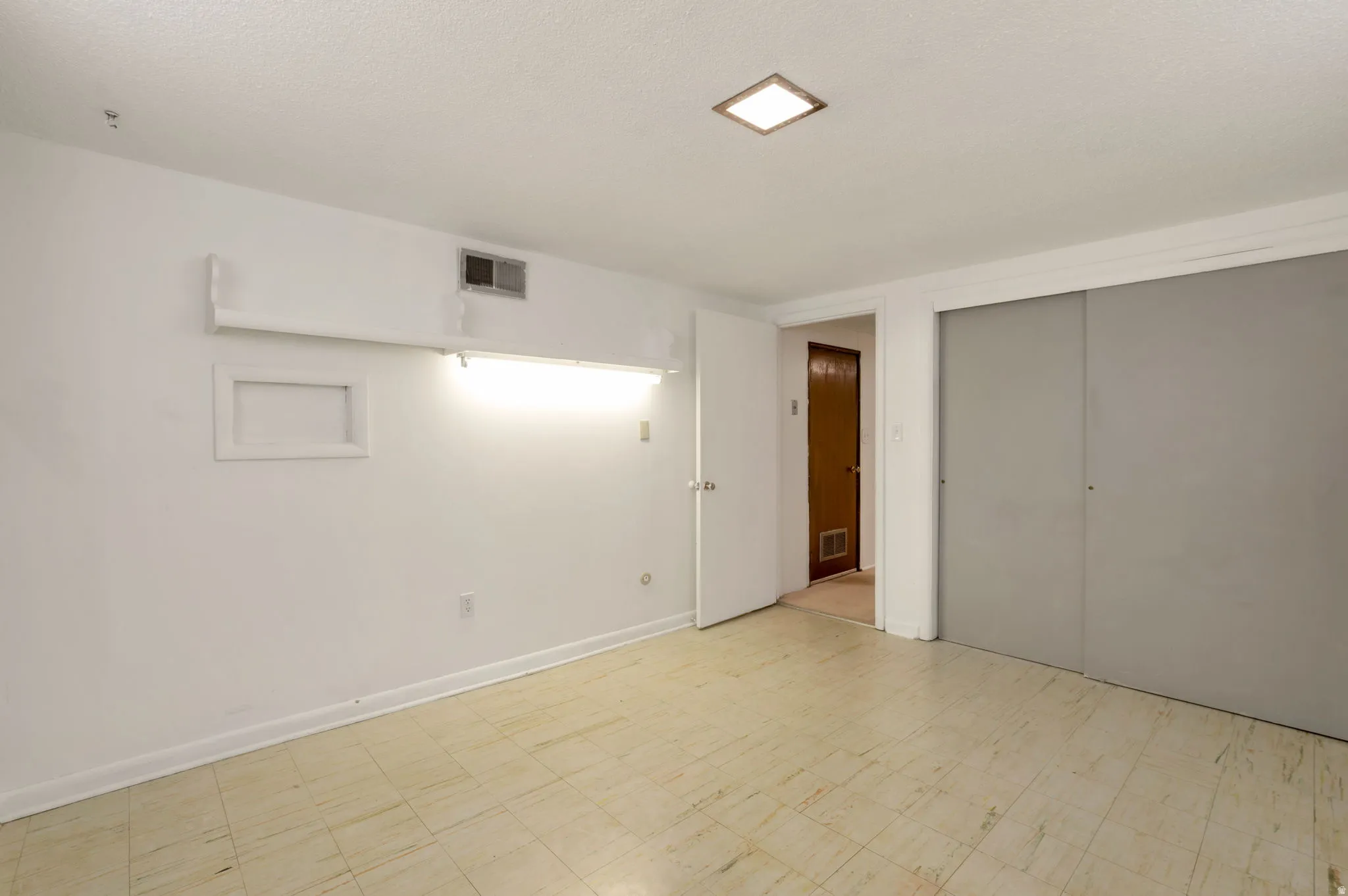 Room with light-toned flooring, featuring a recessed ceiling light and white baseboards