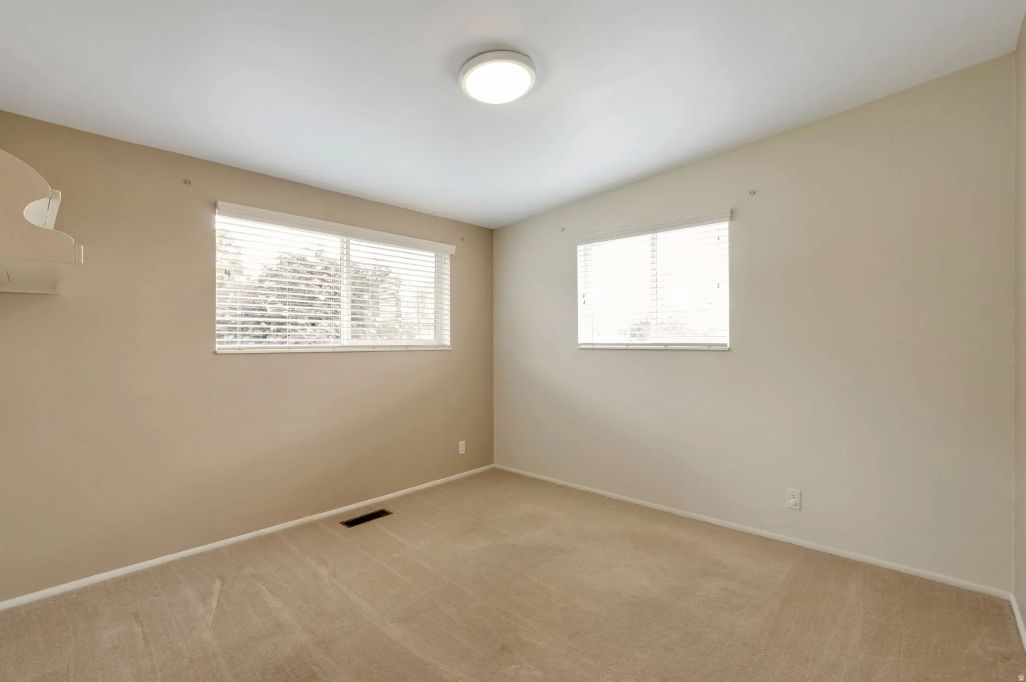 Carpeted room with two windows featuring horizontal blinds