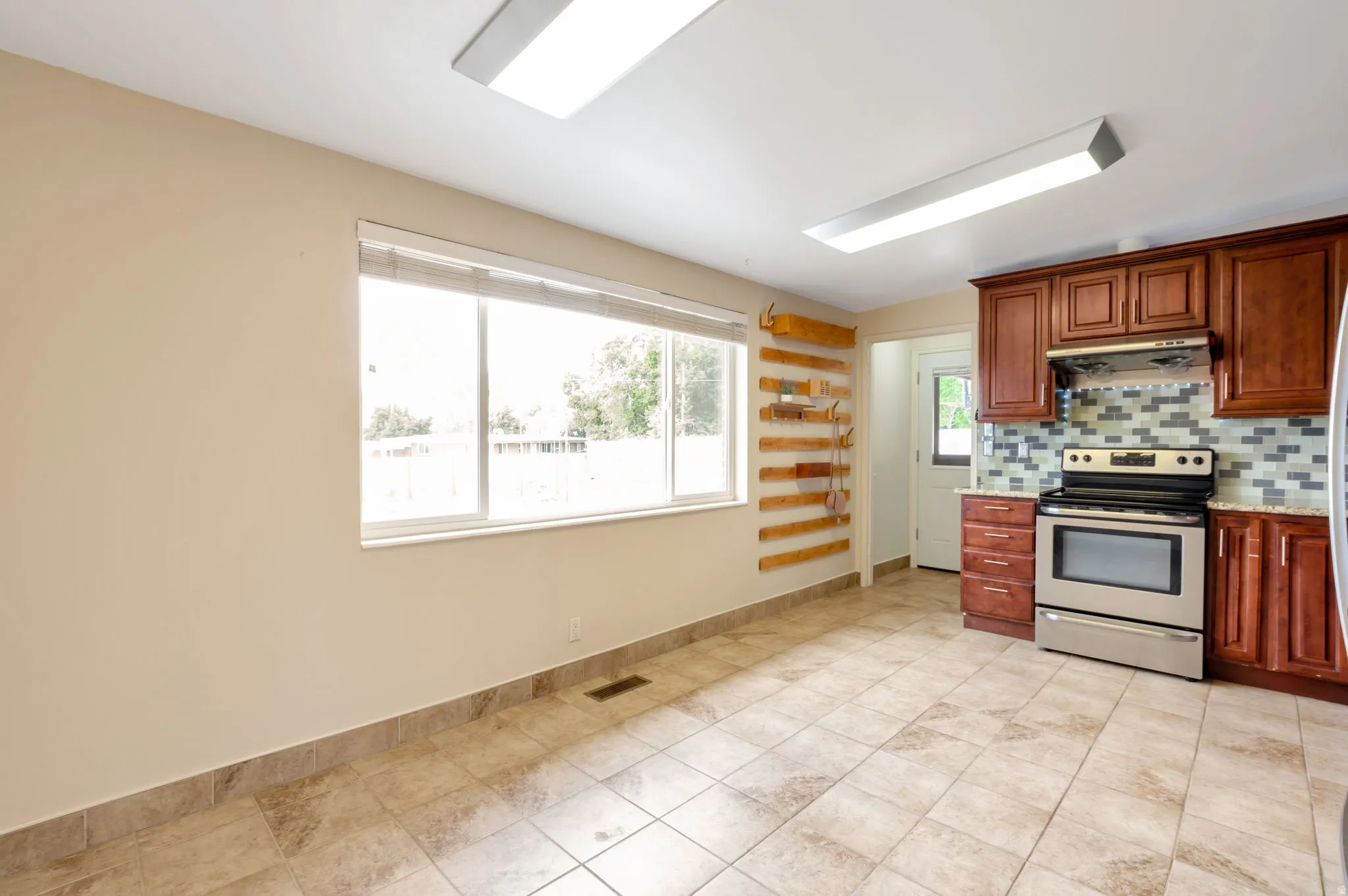 Kitchen featuring wood-finish cabinetry, stainless steel range, and a mosaic tile backsplash