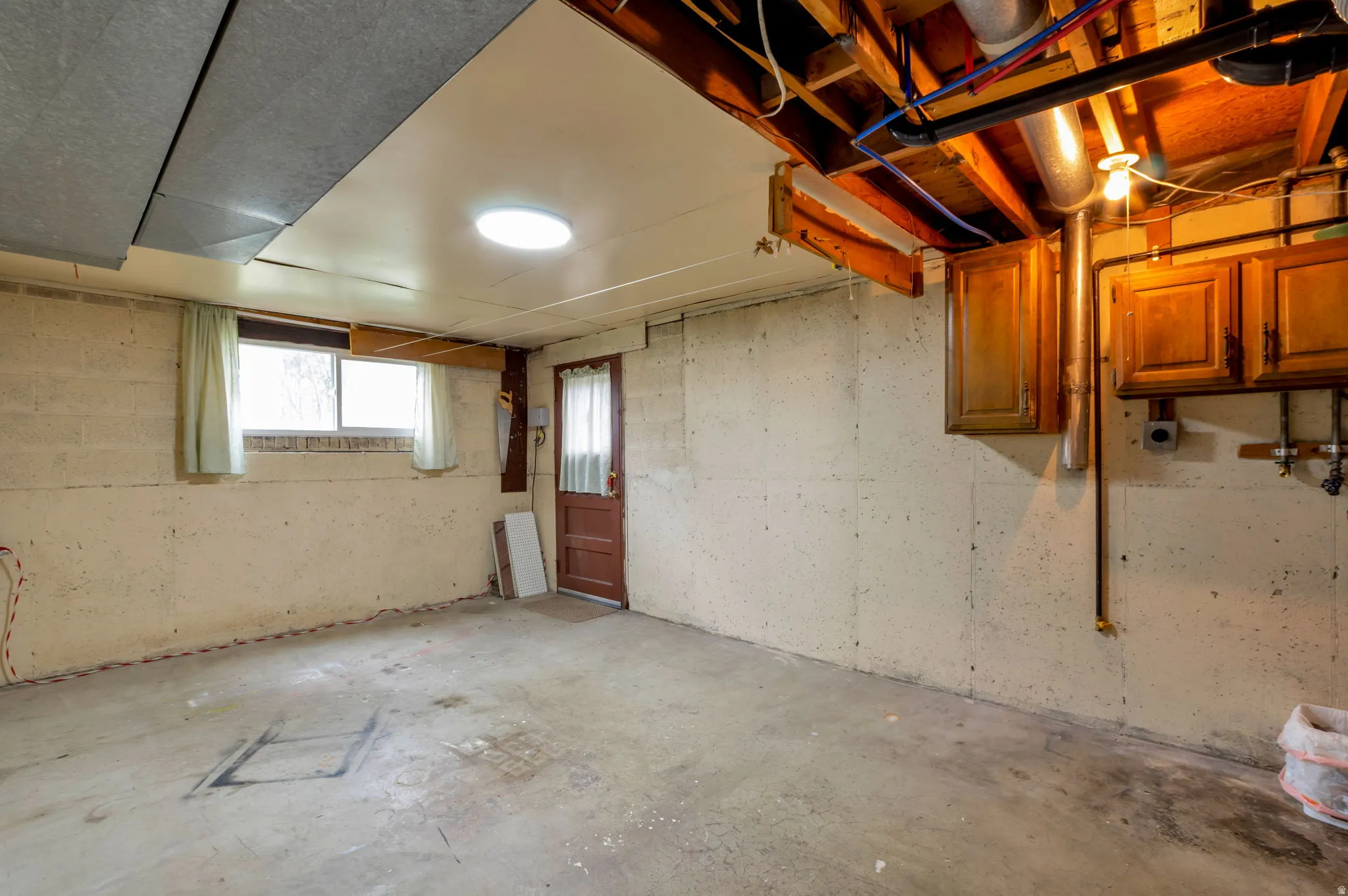 Unfinished basement with concrete flooring and concrete block walls
