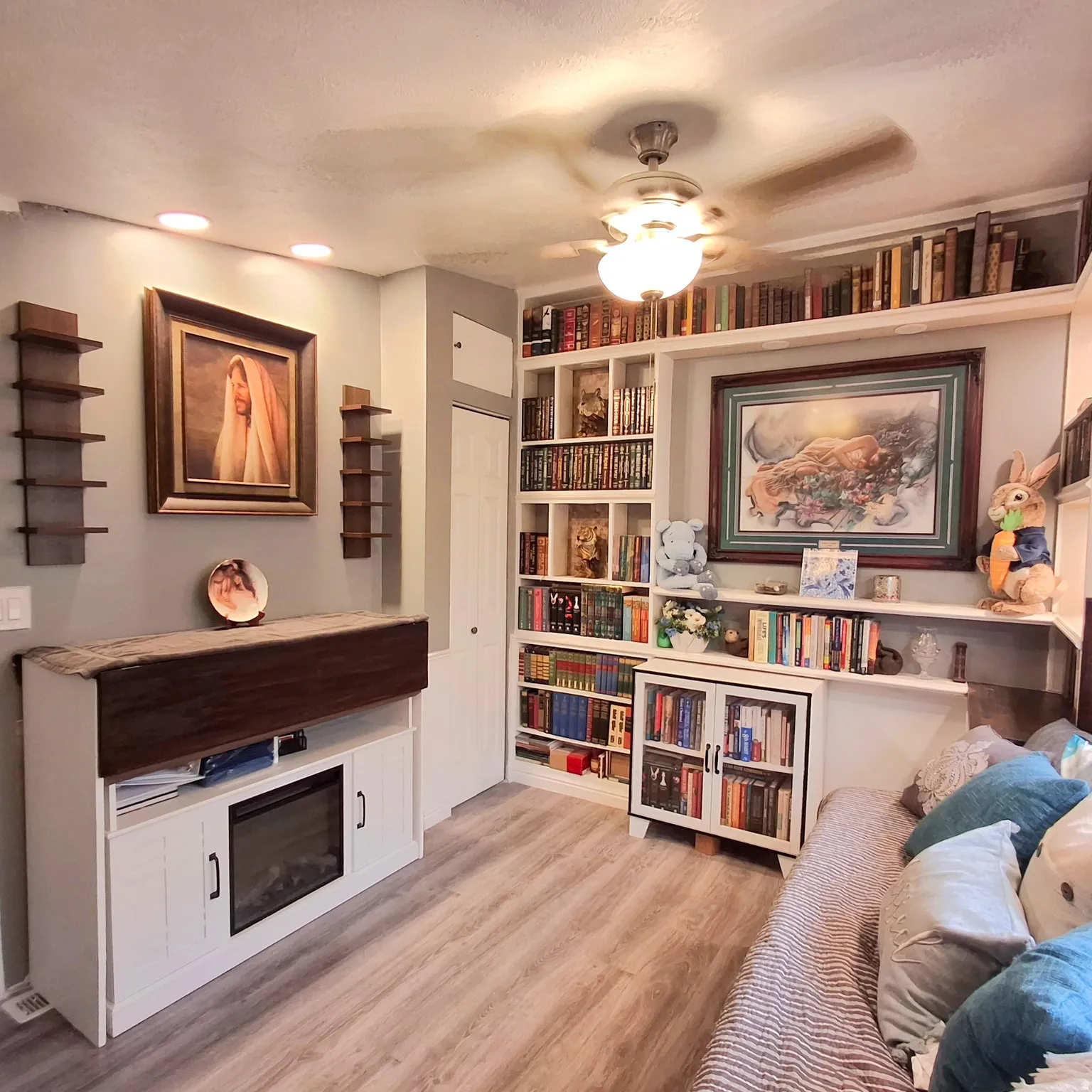 Laminate wood-finish flooring complements extensive built-in shelving, a ceiling fan with integrated lighting, and recessed ceiling lights