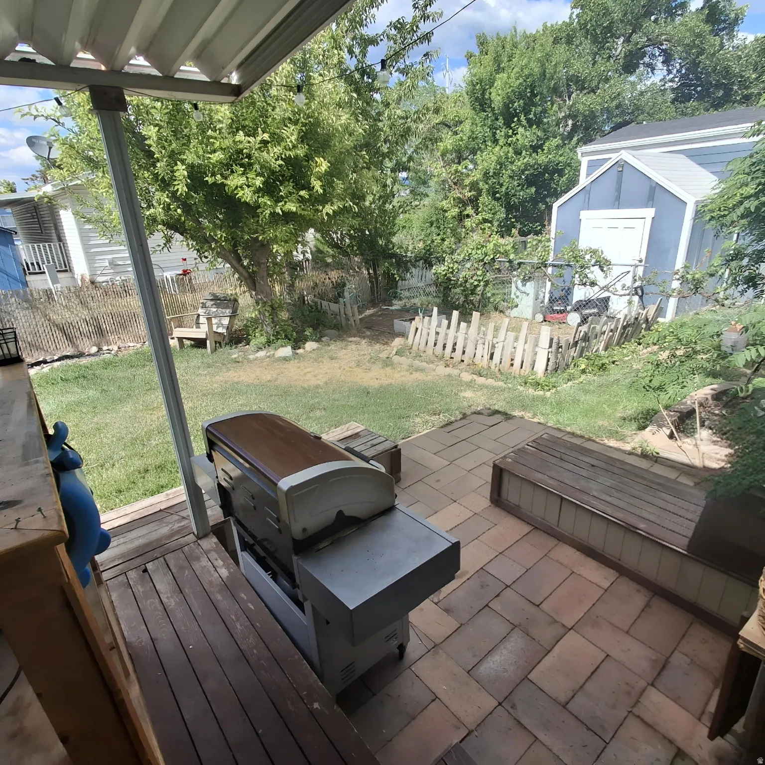 Outdoor patio space featuring a partially covered deck with wood-finish planks, a stone paver patio, and a built-in wood-finish bench