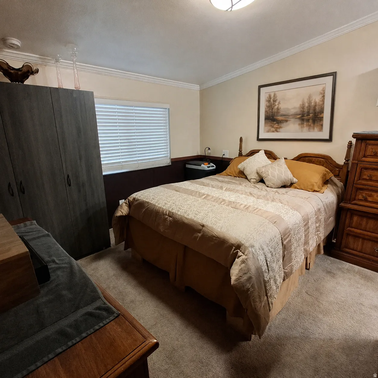 Room featuring neutral-toned walls with a contrasting lower wainscot panel, crown molding, and a carpeted floor