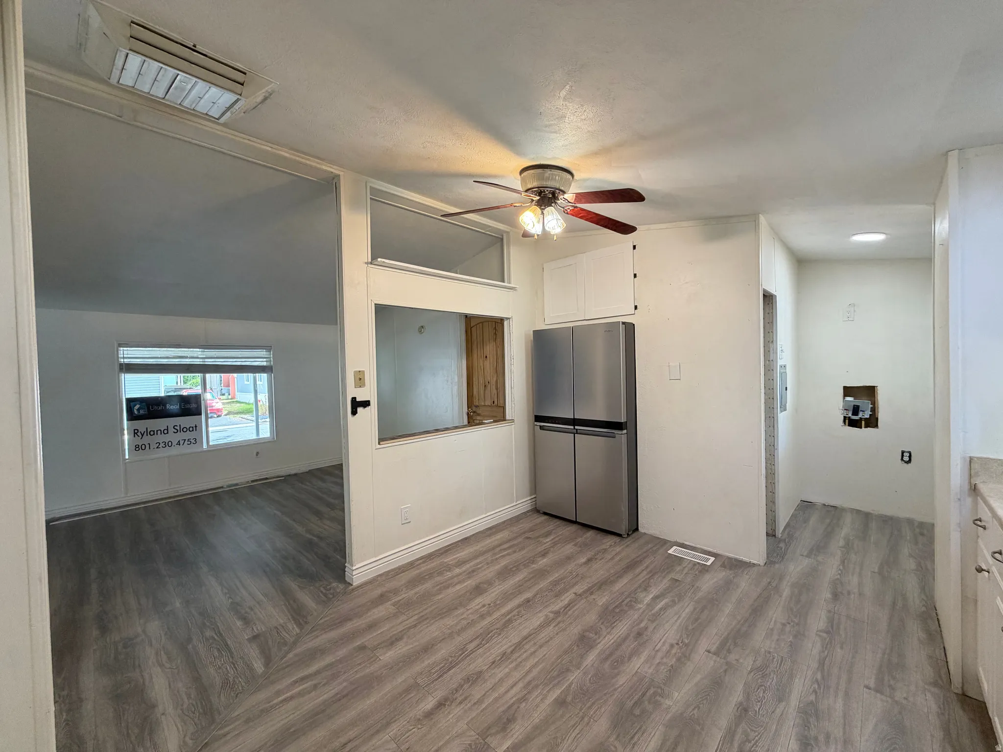 Kitchen area featuring wood-finish flooring, a stainless steel refrigerator, and a ceiling fan