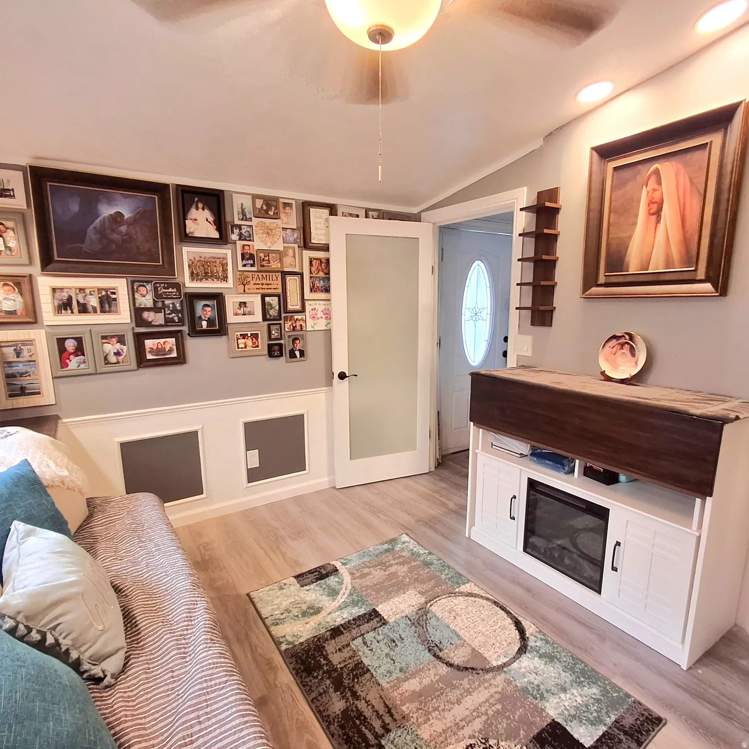 Living space featuring wood-finish flooring, wainscoting, recessed lighting, and a frosted glass-paneled door