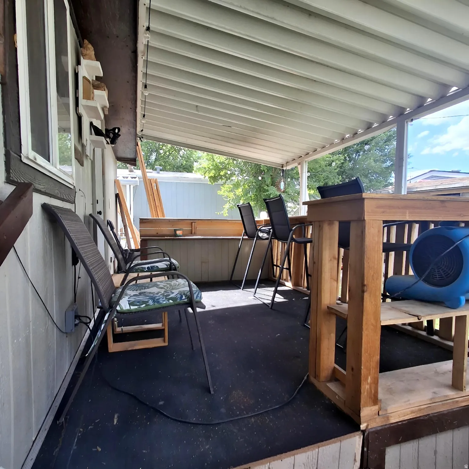 Covered outdoor patio with a built-in wooden bar, white siding, and a slatted ceiling