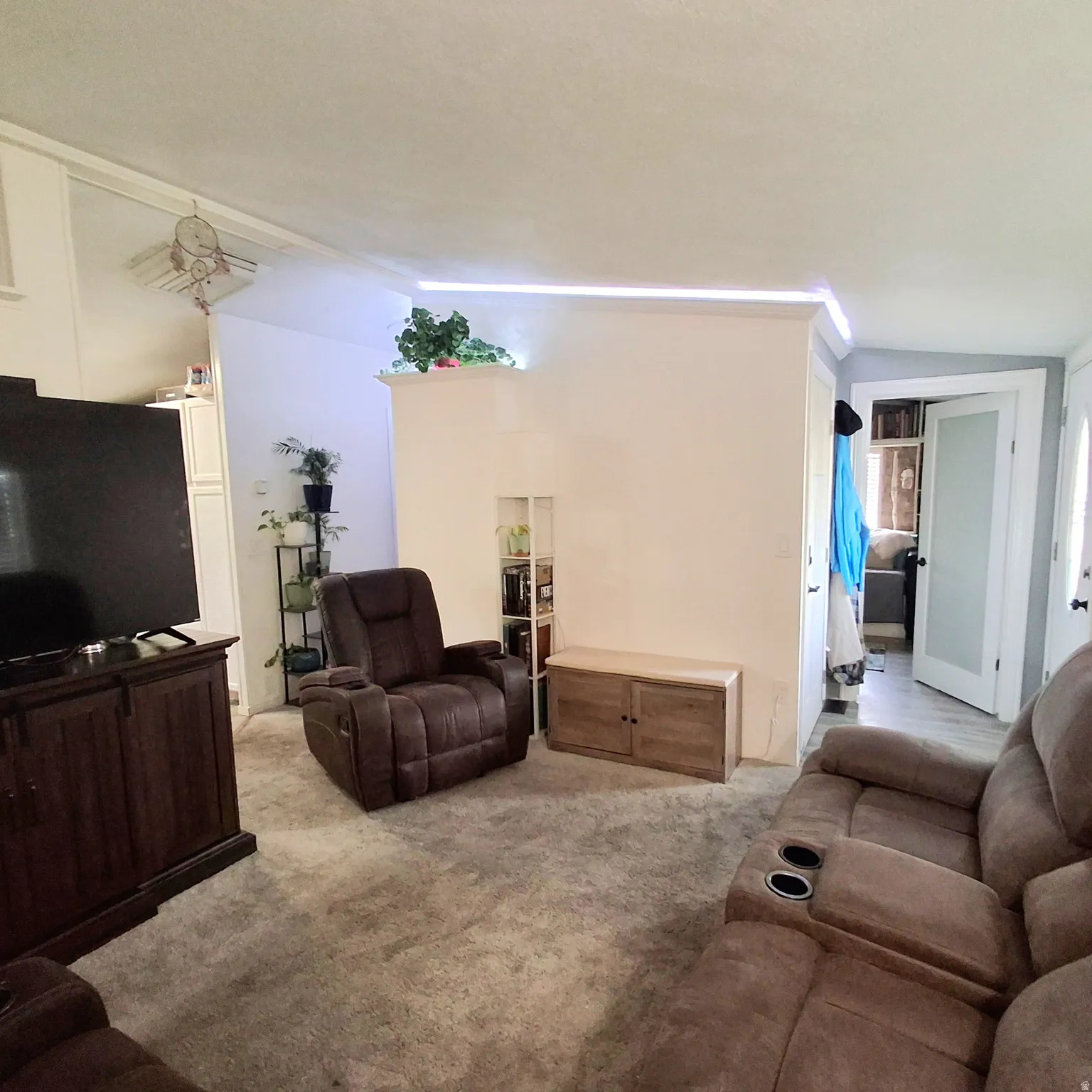 Carpeted living area featuring a built-in partial wall with integrated lighting