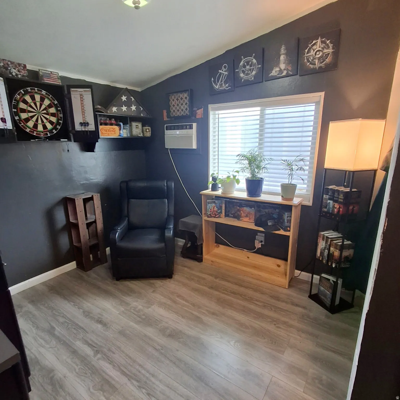Hard-surface flooring extends throughout this room, featuring a window with blinds, a built-in wall air conditioning unit, and recessed lighting