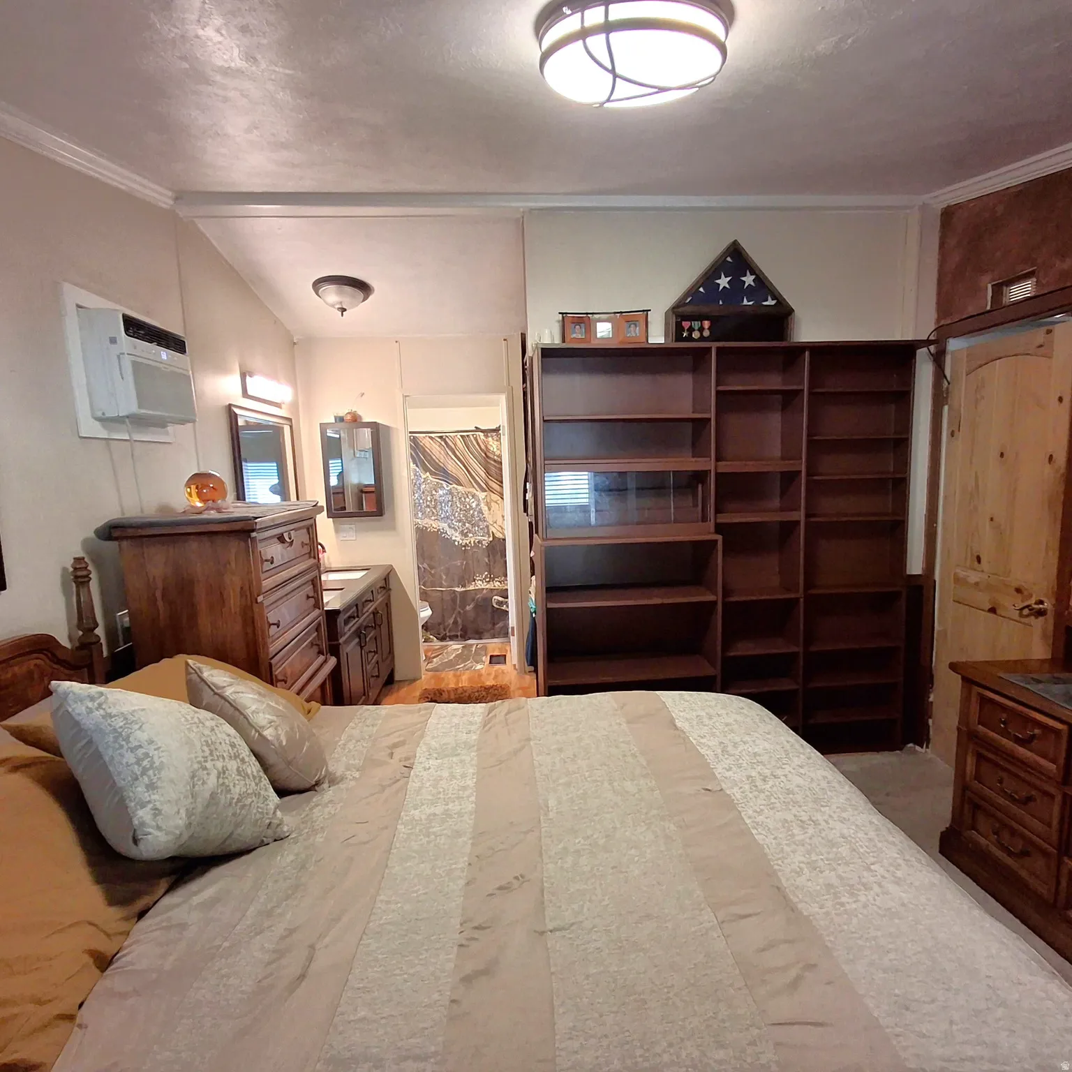 Bedroom featuring built-in shelving, a wood vanity with a basin sink, and a wall-mounted air conditioning unit