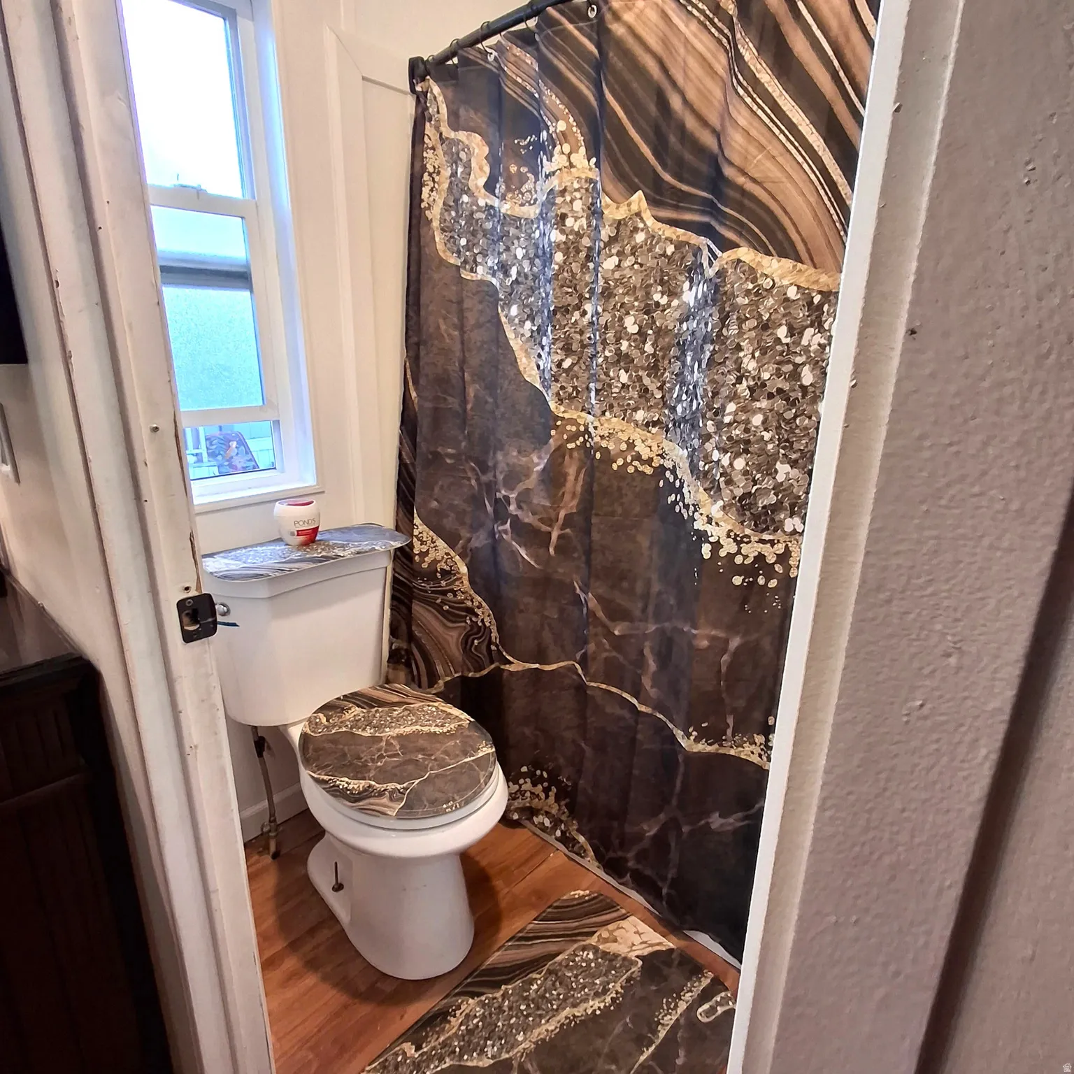 Bathroom featuring a white toilet, wood-finish flooring, and a single window