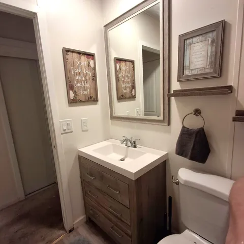 Bathroom featuring a wood-finish vanity with an integrated white sink, a framed mirror, and chrome fixtures