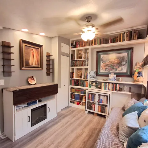 Laminate wood-finish flooring complements extensive built-in shelving, a ceiling fan with integrated lighting, and recessed ceiling lights