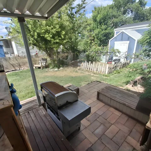 Outdoor patio space featuring a partially covered deck with wood-finish planks, a stone paver patio, and a built-in wood-finish bench