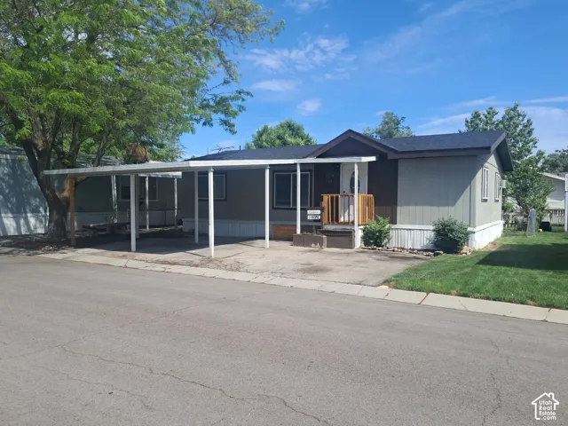Single-story residence featuring light gray siding with white trim, a dark shingle roof, and a covered carport