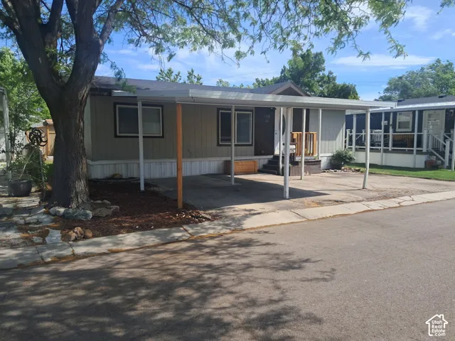 Single-story residence featuring a carport, light beige siding, and a dark brown front door with a small porch