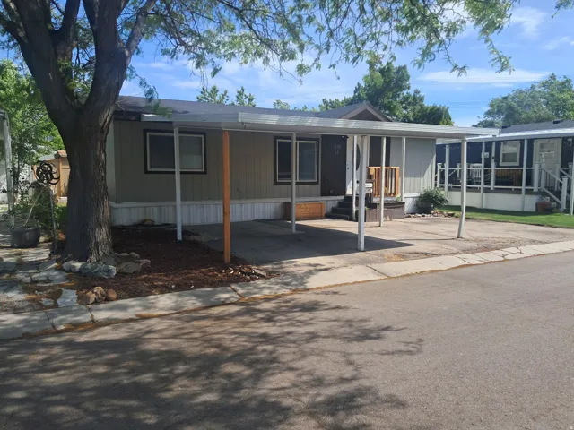 Single-story residence featuring a carport, light beige siding, and a dark brown front door with a small porch