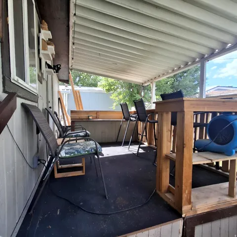 Covered outdoor patio with a built-in wooden bar, white siding, and a slatted ceiling