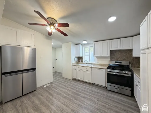 Kitchen featuring wood-finish flooring, white cabinetry, stainless steel appliances, and recessed lighting
