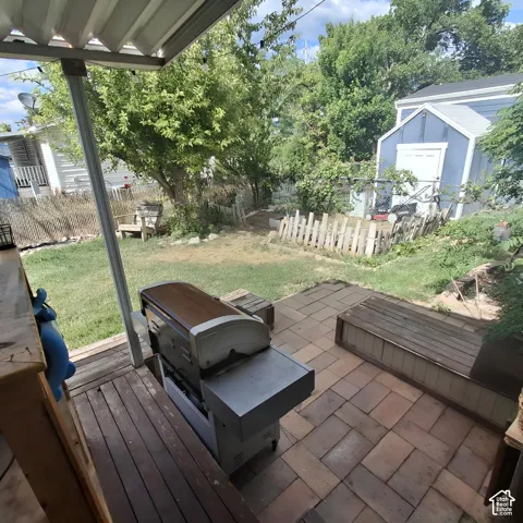 Outdoor patio space featuring a partially covered deck with wood-finish planks, a stone paver patio, and a built-in wood-finish bench