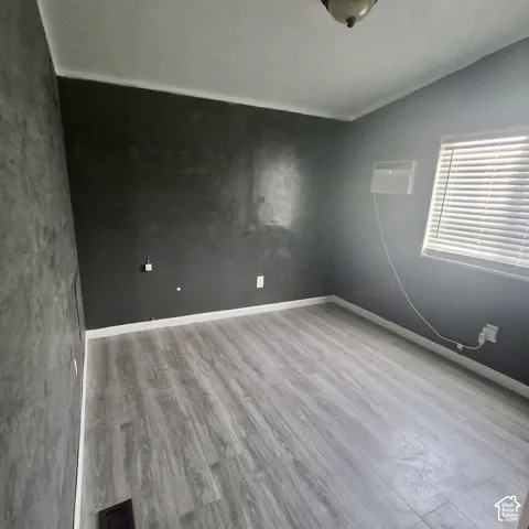 Room with light wood-finish flooring, dark gray walls, and white baseboards