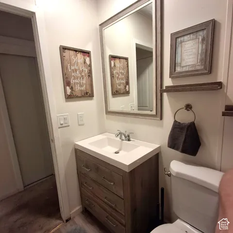 Bathroom featuring a wood-finish vanity with an integrated white sink, a framed mirror, and chrome fixtures