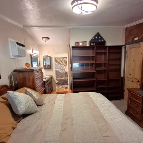 Bedroom featuring built-in shelving, a wood vanity with a basin sink, and a wall-mounted air conditioning unit