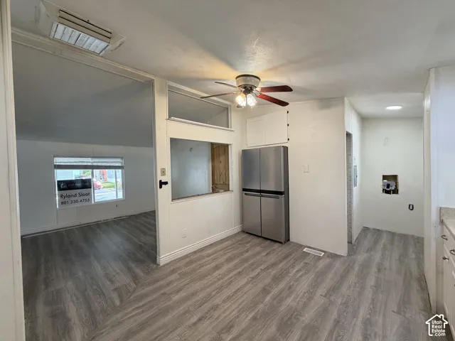 Kitchen area featuring wood-finish flooring, a stainless steel refrigerator, and a ceiling fan