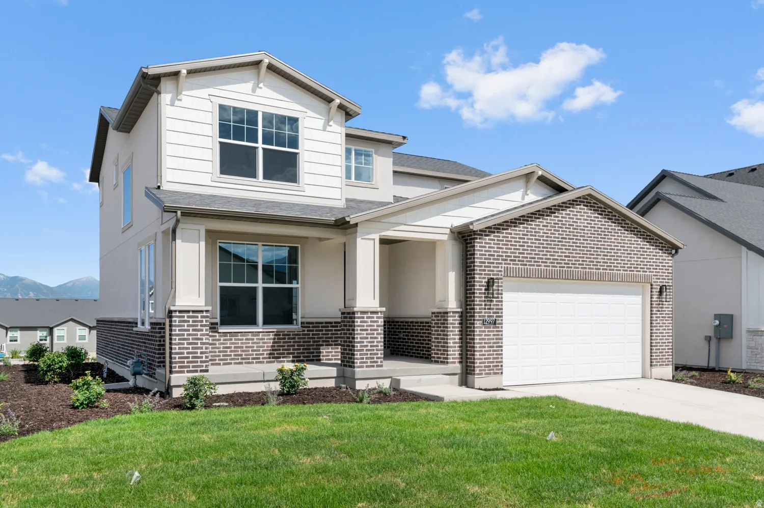 Two-story residence featuring brick and siding facade, an attached garage, and a covered porch entry