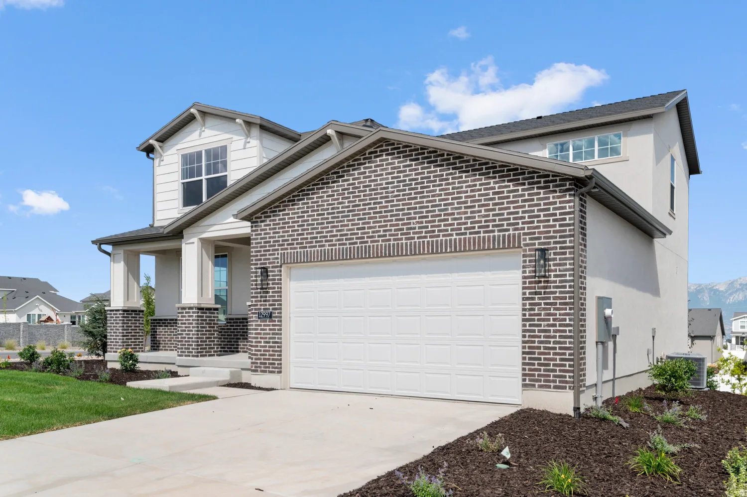 Two-story residence featuring a brick facade, stucco siding, and a covered front porch with square columns