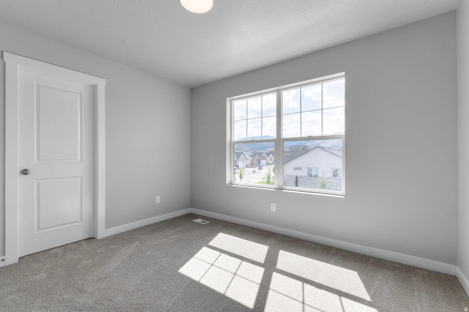 Spacious room featuring neutral grey walls and new grey carpeting