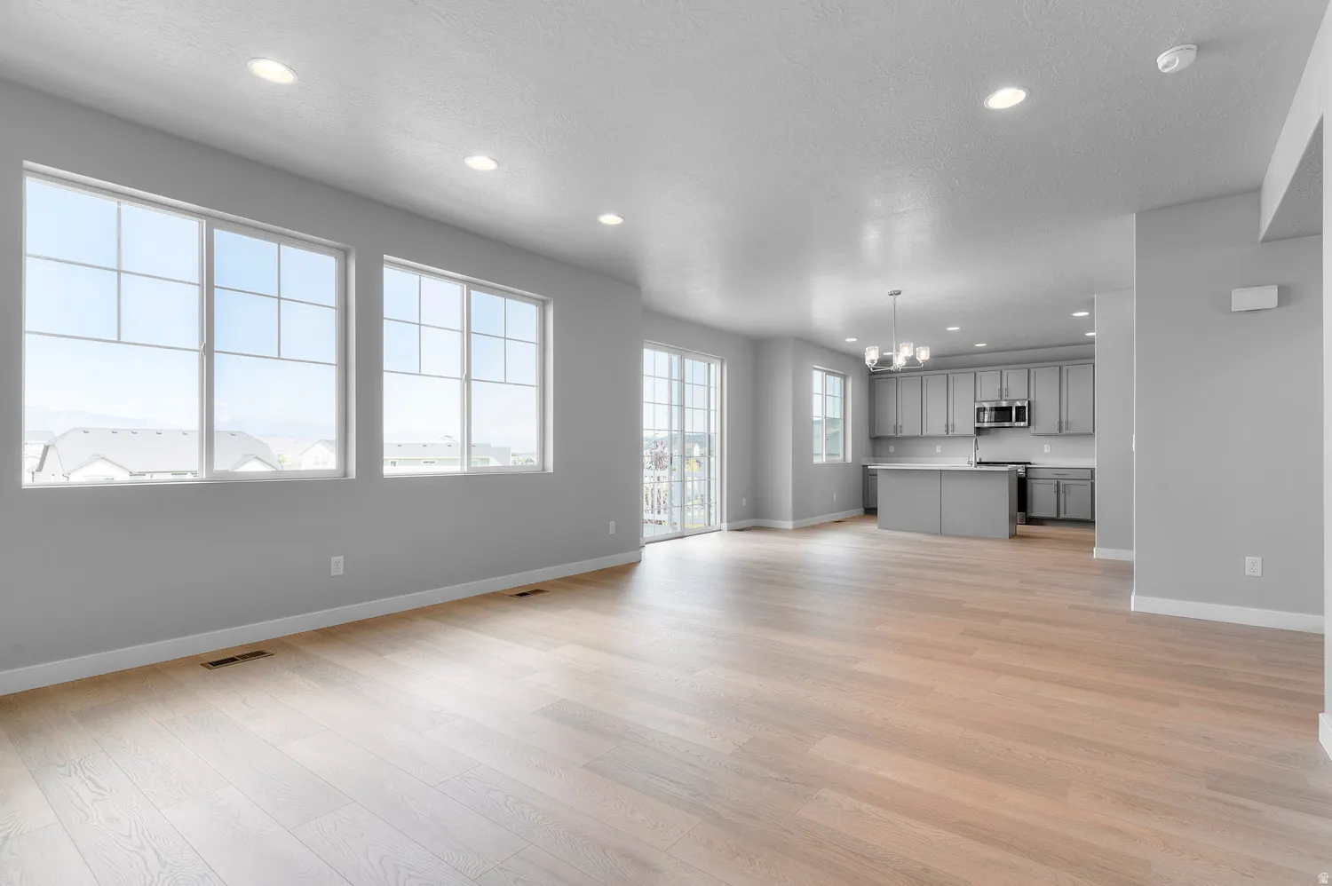 Spacious open concept living area featuring light wood-finish flooring and recessed lighting