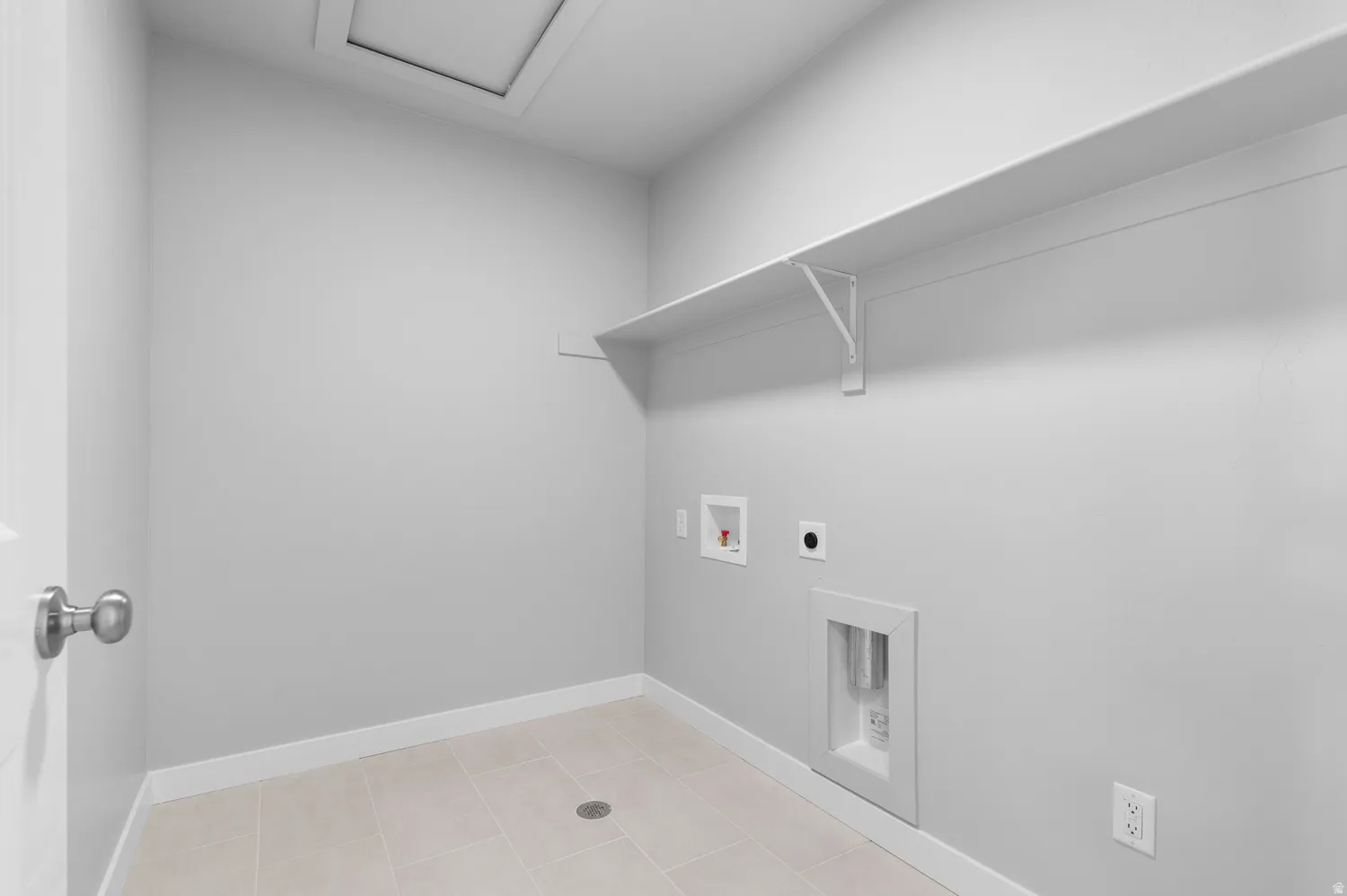 Utility room featuring a built-in shelf, neutral wall color, tile flooring, and a floor drain