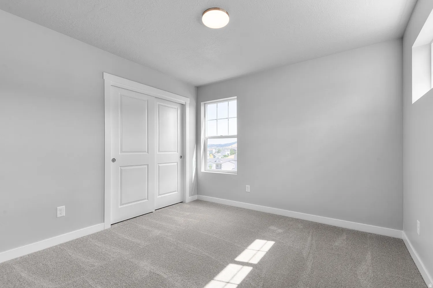 Carpeted room featuring a double-pane window, flush-mount ceiling light, white trim, and a bi-fold closet