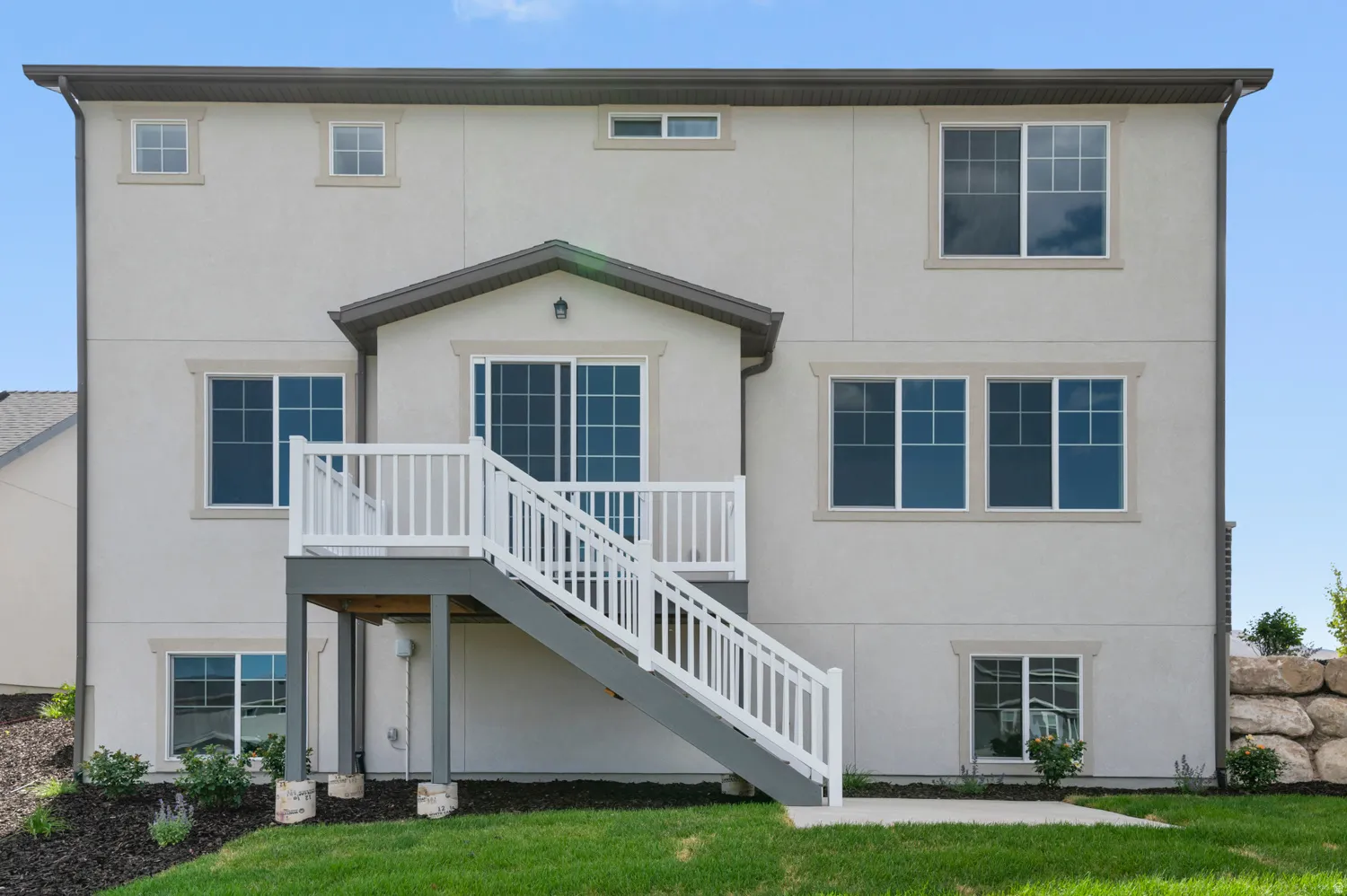 Rear exterior featuring a multi-level deck with white railings, a sliding glass door, and multiple windows with light-colored trim