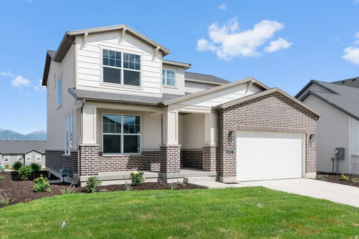 Two-story residence featuring brick and siding facade, an attached garage, and a covered porch entry