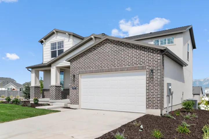 Two-story residence featuring a brick facade, stucco siding, and a covered front porch with square columns