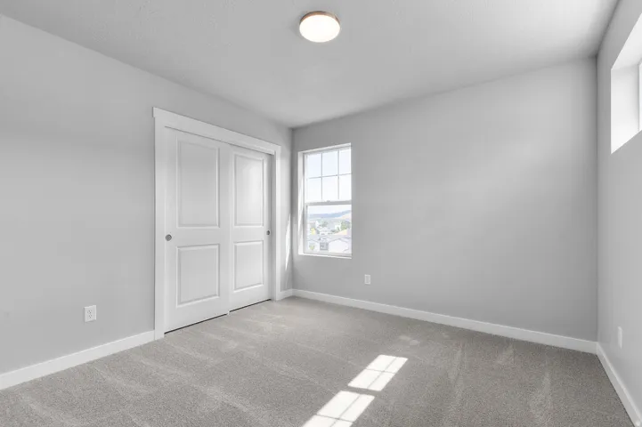 Carpeted room featuring a double-pane window, flush-mount ceiling light, white trim, and a bi-fold closet