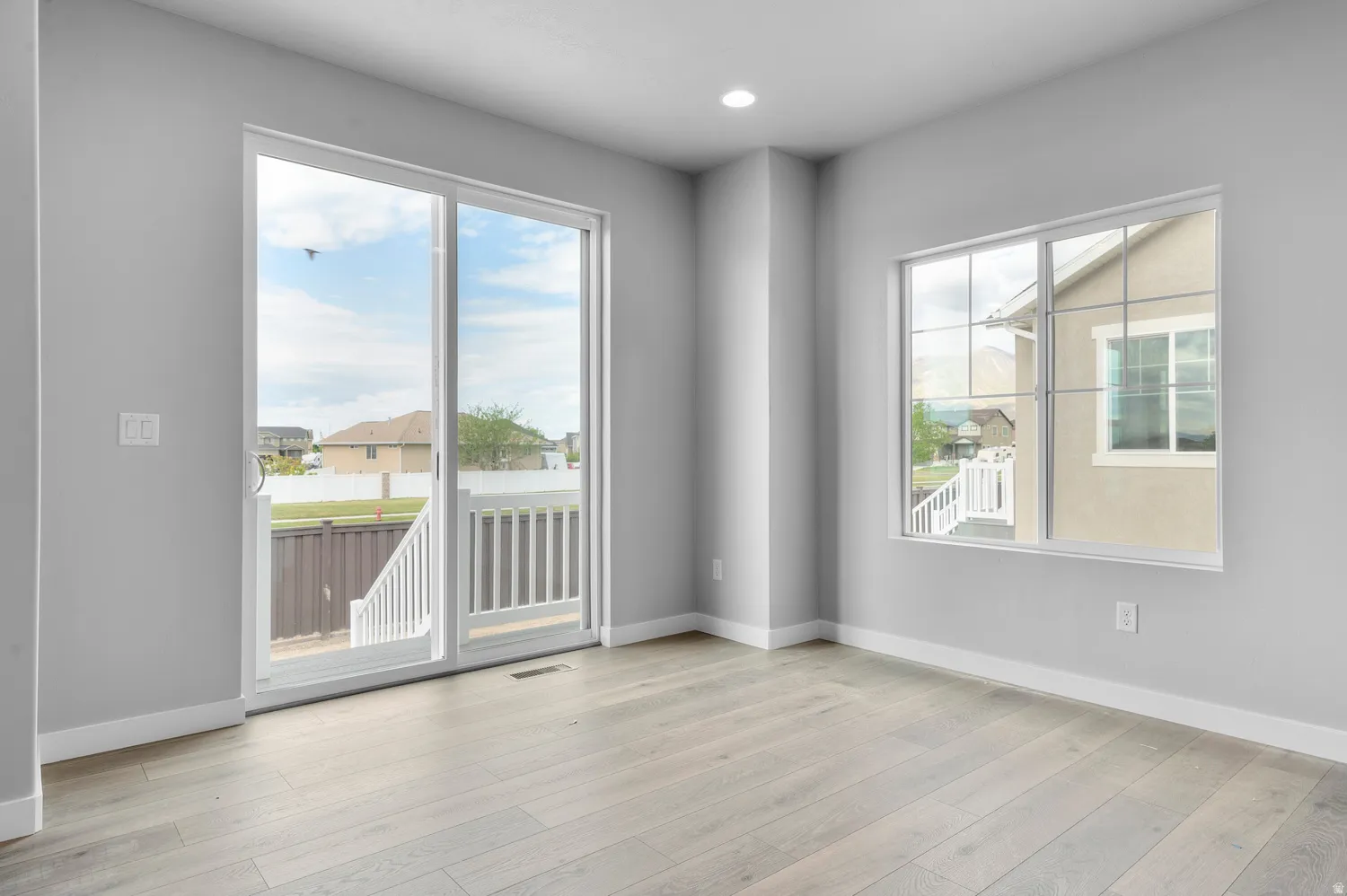Room featuring light gray walls, wood-finish flooring, and white baseboards