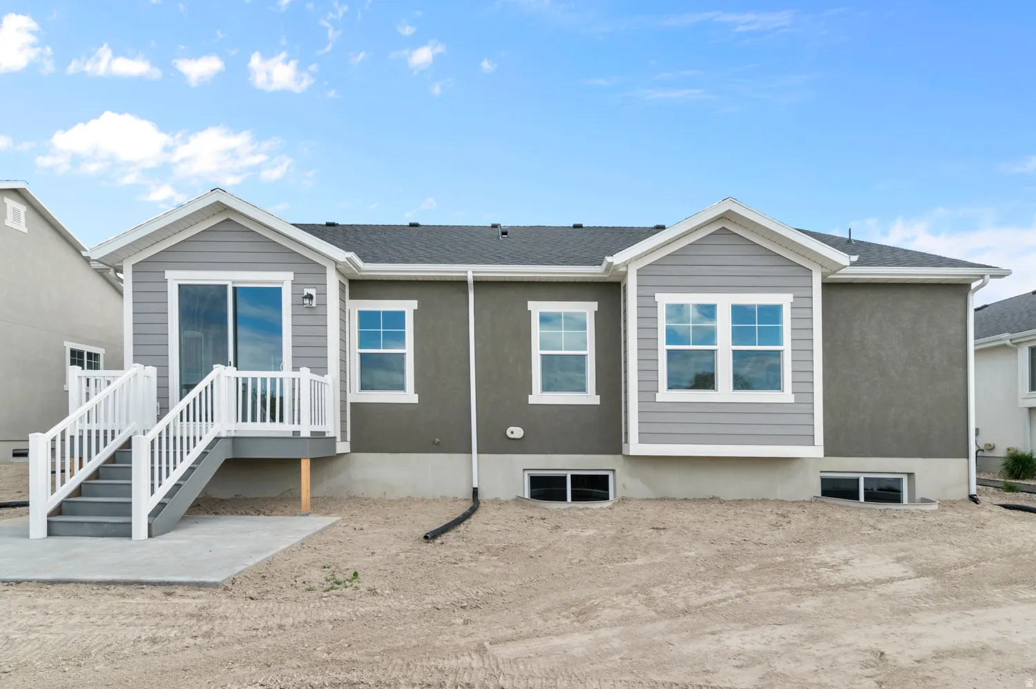 Rear exterior featuring a sliding glass door with balcony and stairs to a concrete patio