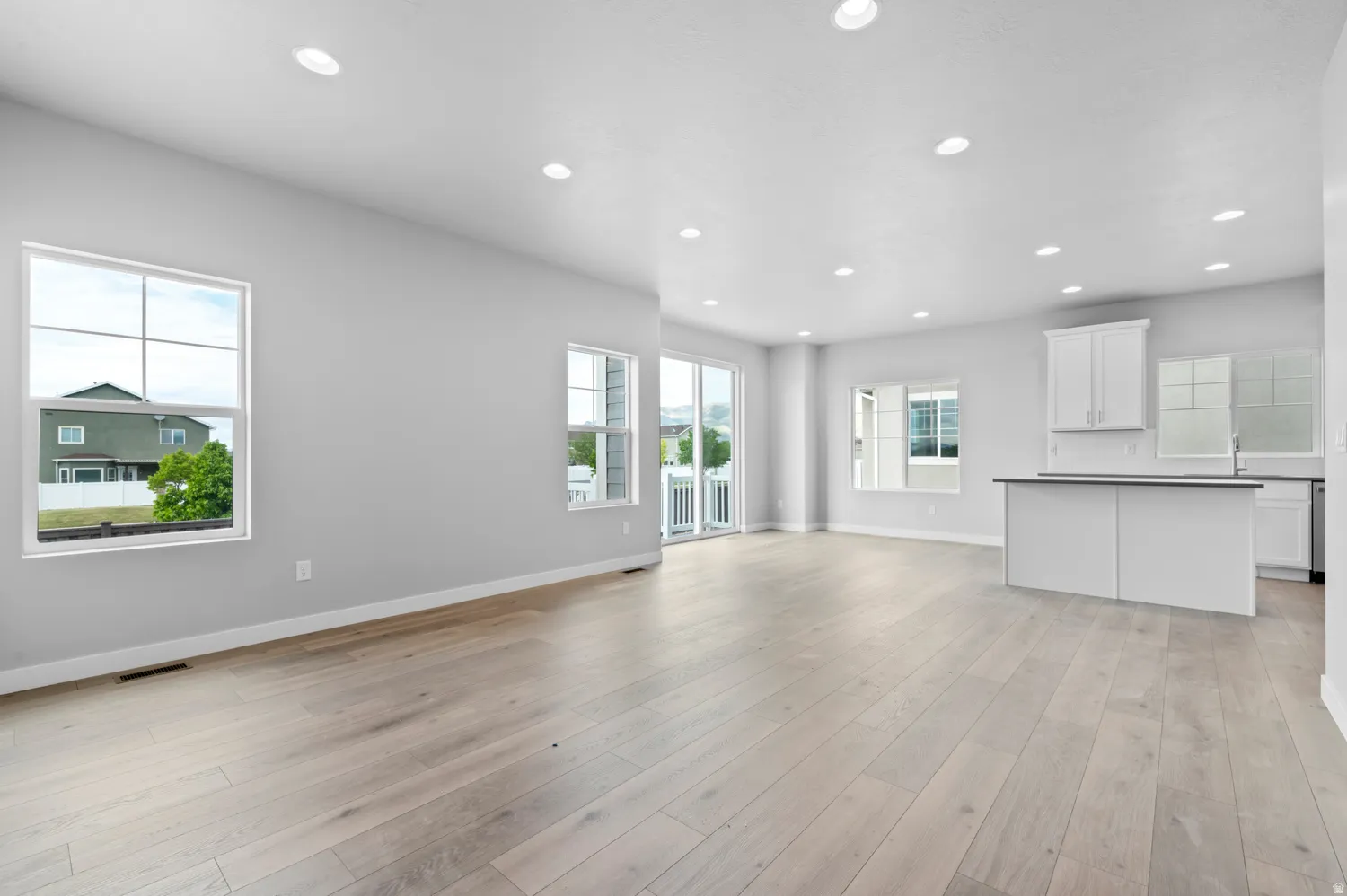Open-concept living space featuring light wood-finish flooring, recessed lighting, and expansive windows