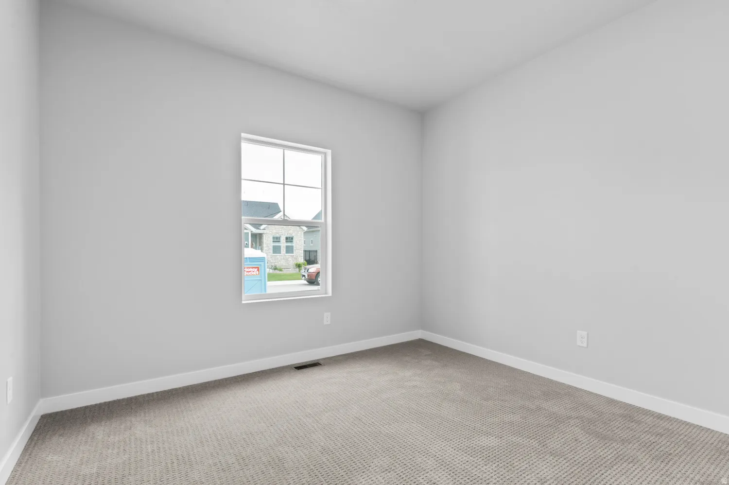 Carpeted room featuring a white-framed window, light gray walls, and white baseboards