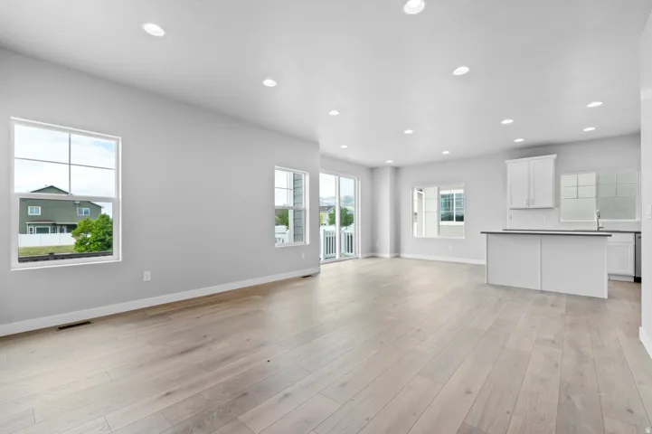 Open-concept living space featuring light wood-finish flooring, recessed lighting, and expansive windows