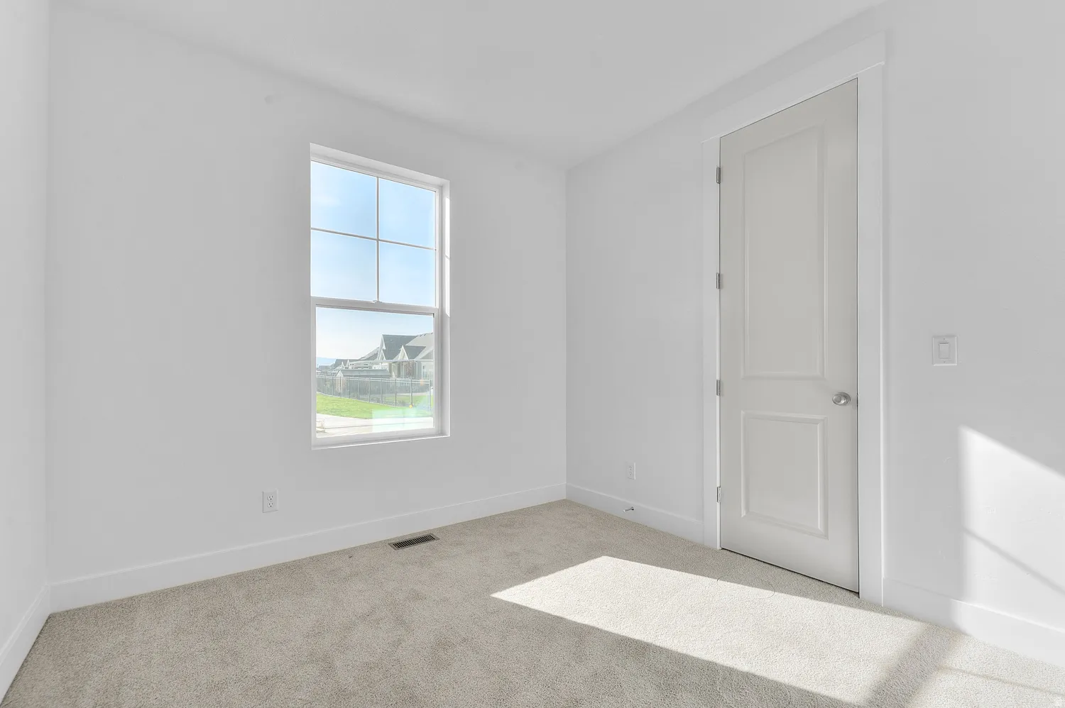 Carpeted room with a double-pane window, white trim, and a paneled interior door