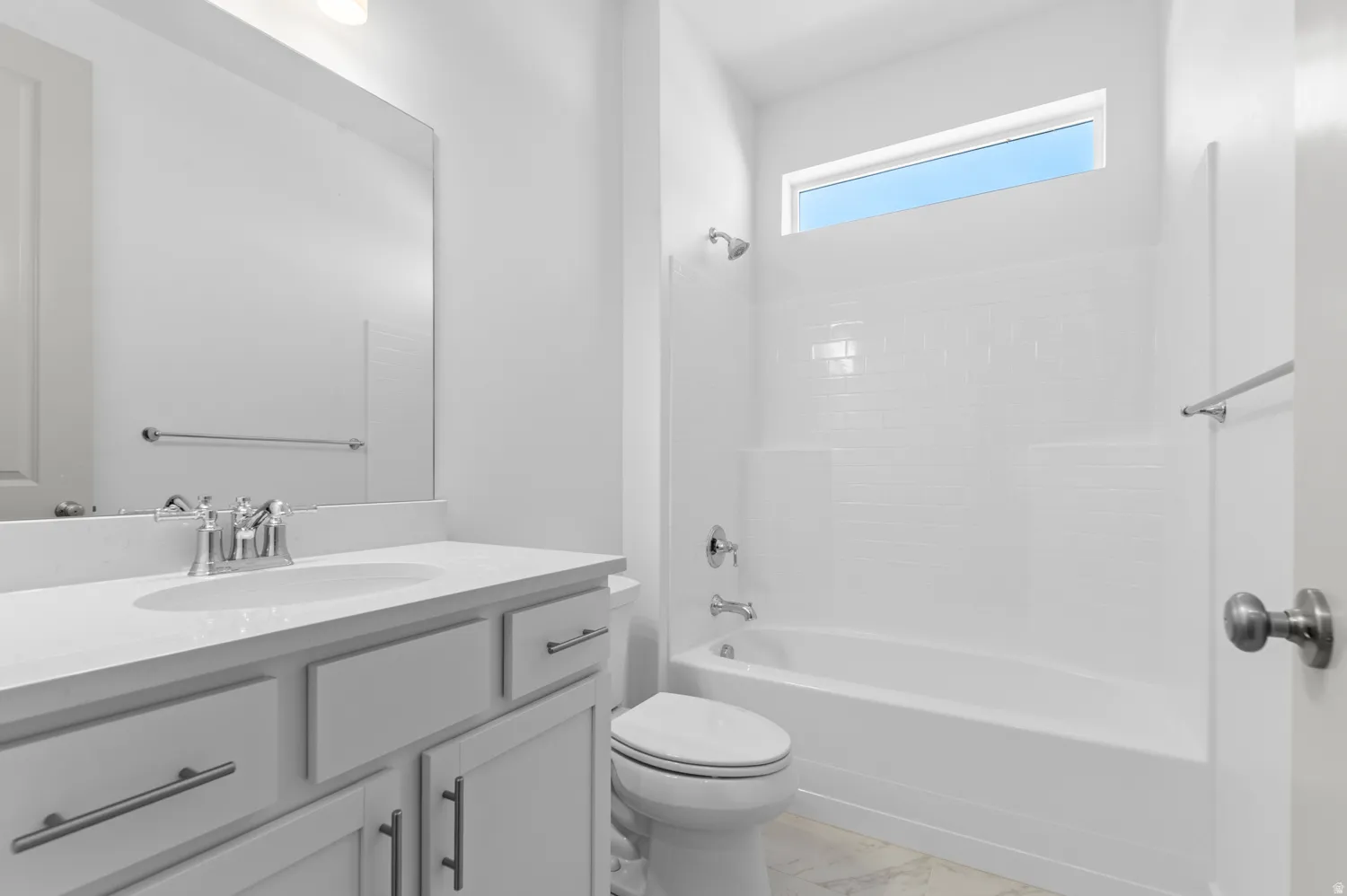 Modern bathroom featuring a white vanity with an undermount sink, chrome faucet, and ample counter space