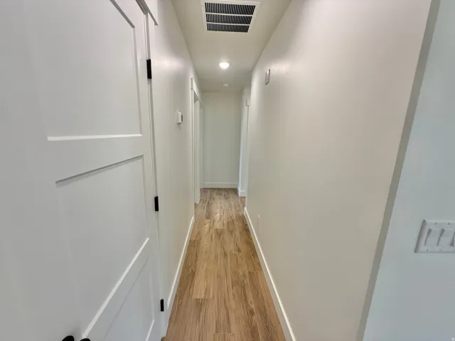 Wood-finish flooring throughout, complemented by white walls and recessed lighting