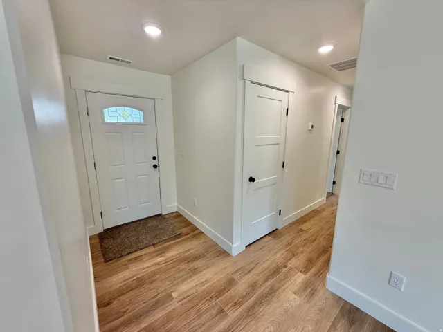 Entryway featuring wood-finish flooring, recessed lighting, and a white paneled door with stained glass detail