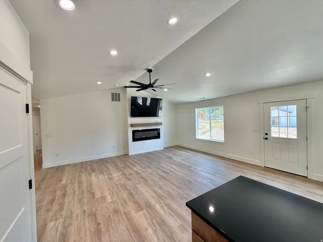 Bright, open-concept living space featuring recessed ceiling lighting, a ceiling fan, and wood-finish flooring throughout